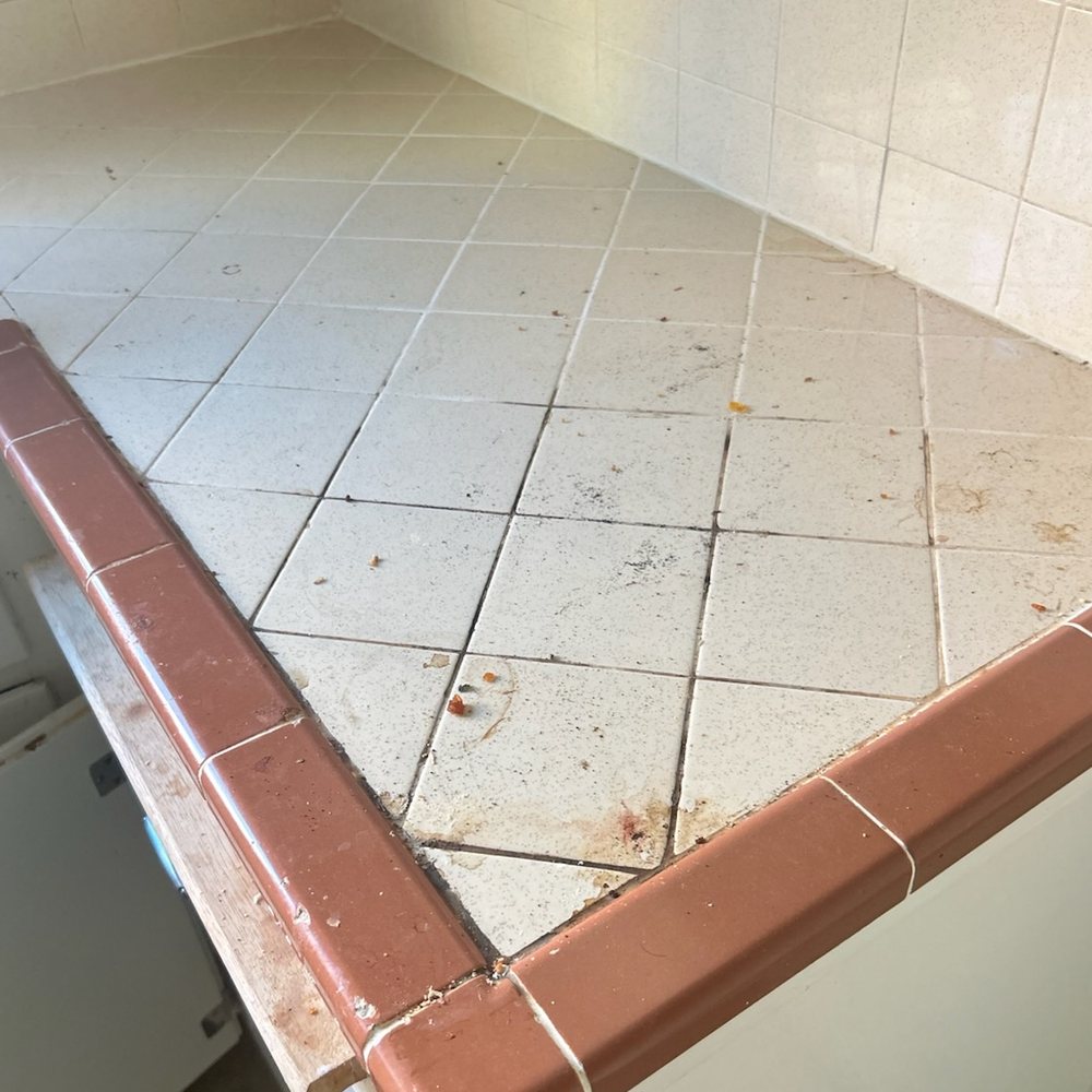 Tiled kitchen counter before and after a deep clean — before