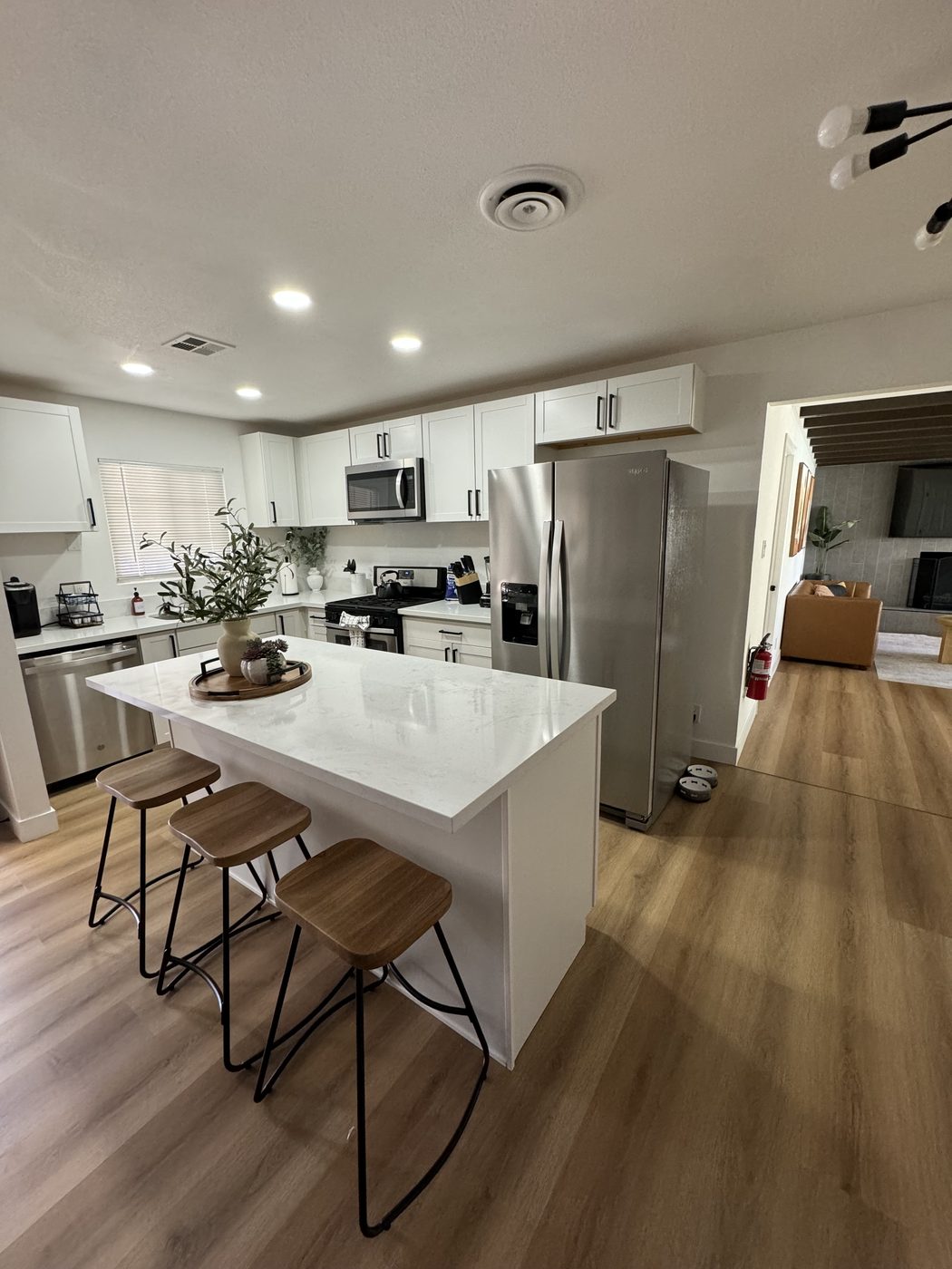 Open kitchen with white quartz island and stainless appliances after cleaning